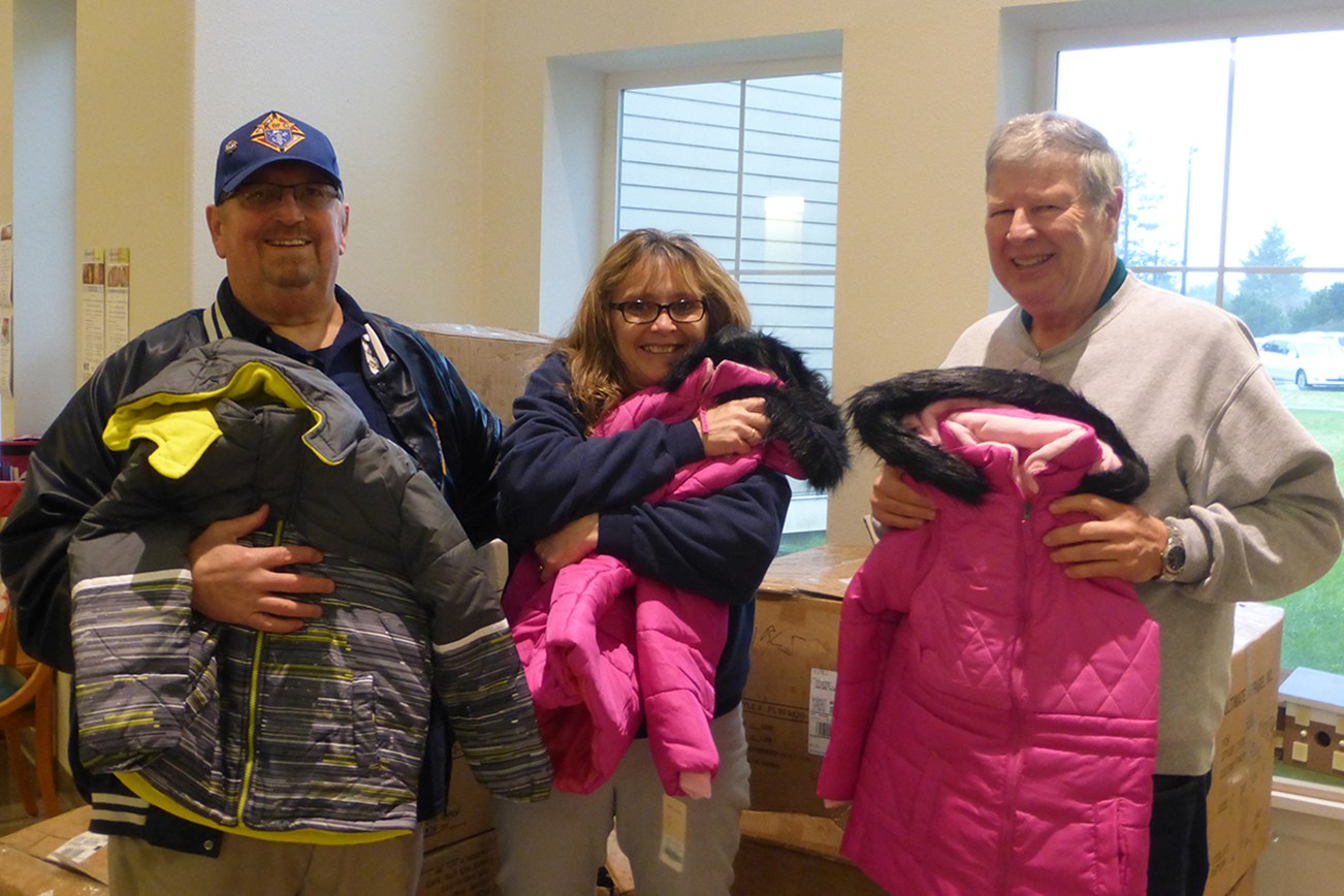 Photo by Kristin Hieronymus: The Knights of Columbus and members of St. Jerome Catholic Church last week presented boxes of winter jackets for students in the North Beach School District to Ocean Shores Elementary Principal Rhonda Ham, center, with Bob Hakanson and John Balmer doing the presentation.