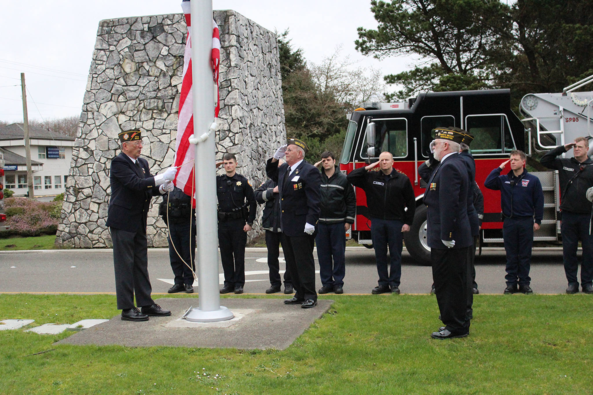 Angelo Bruscas/North Coast News photo: Members of VFW Post 8956, with Dennis Hogan, Dan Martin, John Link, and Jim Docherty, present the flag with Ocean Shores firefighters in the background.