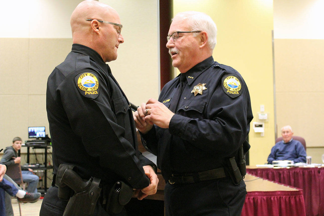 Angelo Bruscas/North Coast News                                Retiring Ocean Shores Police Chief Mike Styner, right, pins the badge on new Police officer J.J. Justman on Monday night.