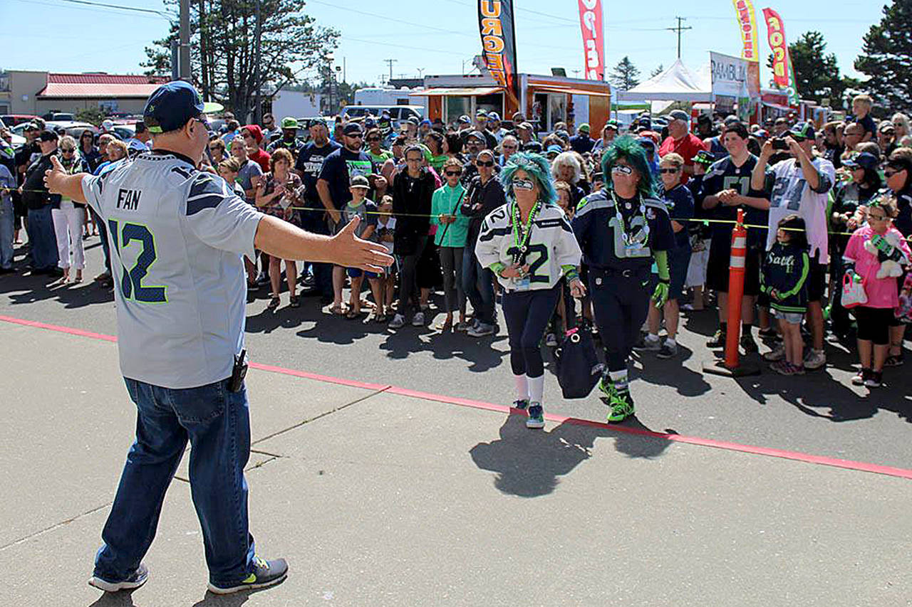 Angelo Bruscas/North Coast News: Event organizer Terry Johnson of the Mighty 12’s Alliance Seahawks fan organization greets Mr. and Mrs. Seahawk (Jeff and DeDe Schumaier of Auburn) before the raising of the 12th Man flag at the Ocean Shores Convention Center in 2016.