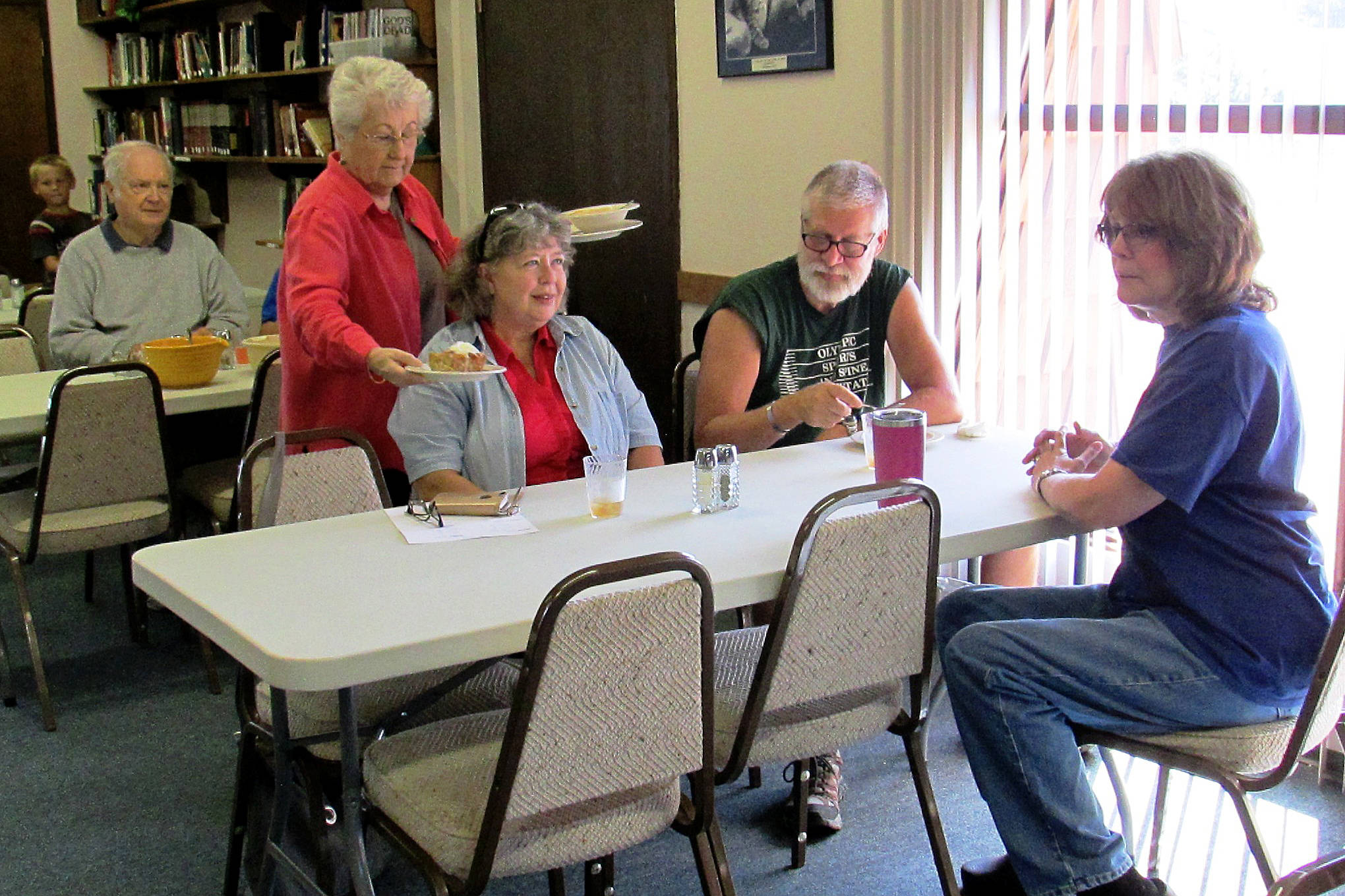 Scott D, Johnston photo Volunteer Connie Jones serves patrons at the Grace Cafe, while Pastor Collette Gould, far right, looks on. A free community meal is served from 11 a.m. to 1 p.m. each Friday at Galilean Lutheran Church in Ocean Shores.
