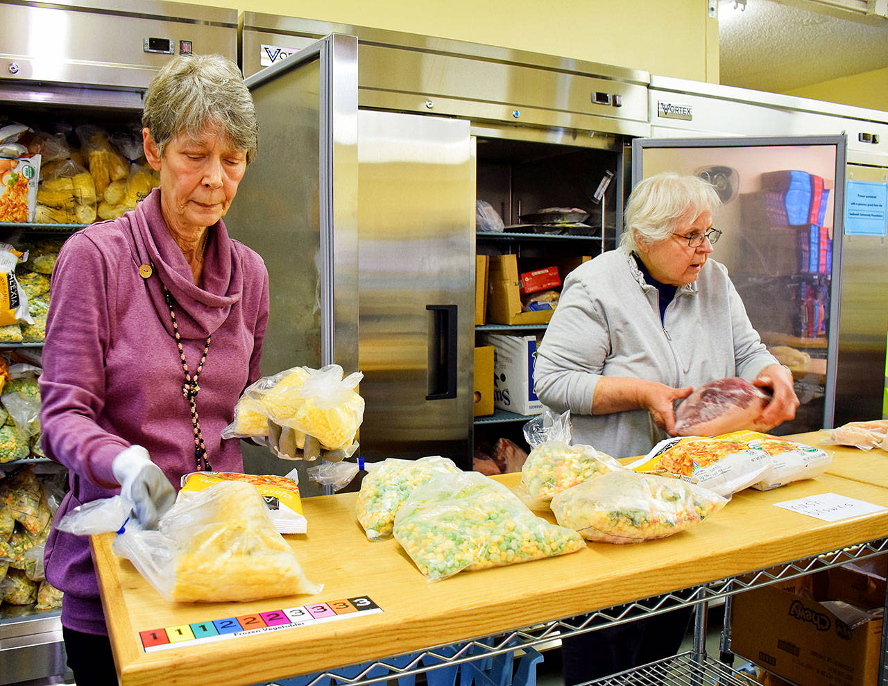 Caption: Ocean Shores Food Bank volunteers Myriam Moist, left, and Arlene Stephenson, take frozen vegetables and meats out of the three new freezers the Food Bank recently purchased with part of a $10,000 from the Seabrook Community Foundation. Photo by Scott D. Johnston
