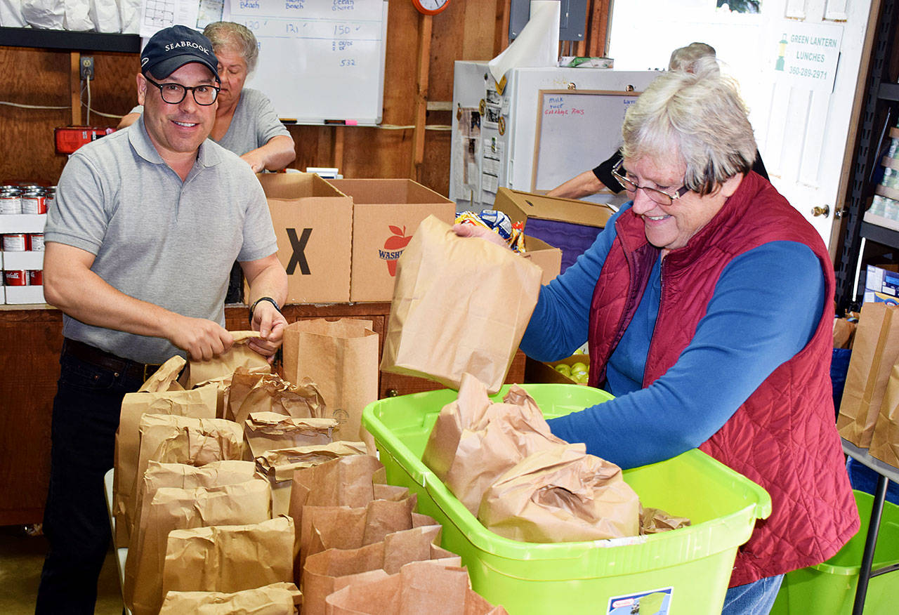 Scott D. Johnston photos: Stephen Poulakas and Lois Ann Shatto load lunch bags into tubs for the Pacific Beach route for Green Lantern Lunches.