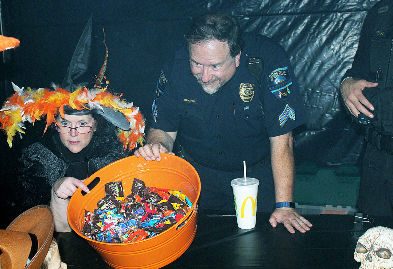 Angelo Bruscas/North Coast News: Ocean Shores Police Sgt. David McManus keeps watch on the stock of candy at the department’s booth at the Convention Center for the Halloween Party for Kids sponsored by the Ocean Shores Firefighters Association and Department.
