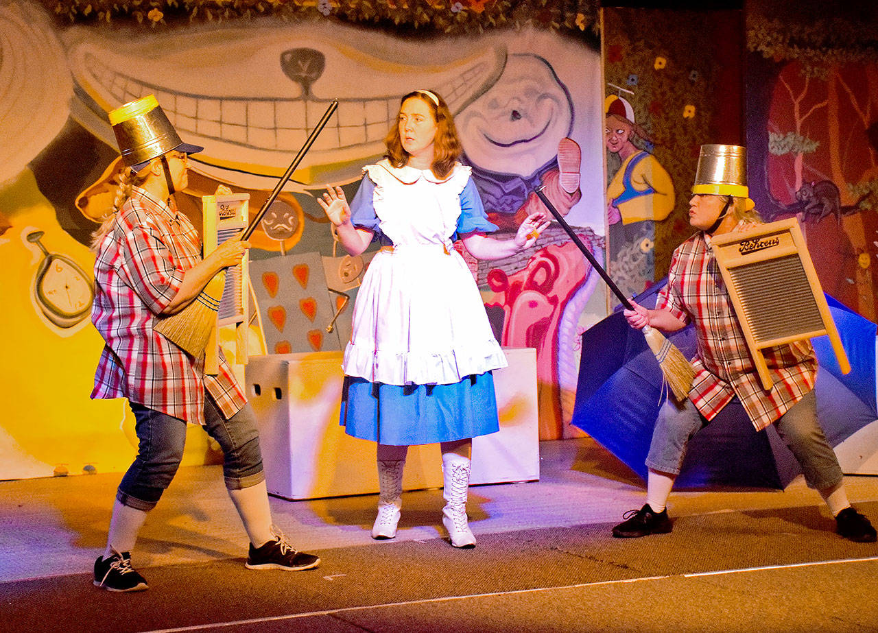 In a scene from the Stage West Community Theatre production of “Alice in Wonderland,” Alice (Joni Chism) finds herself in the middle as Tweedledee (Pamela Nygaard on right) and Tweedledum (Cai Hadfield) prepare for battle with brooms, buckets and washboards. The play runs May 3-12 at the Ocean Shores Lions Club. (Photo by Scott D. Johnston)