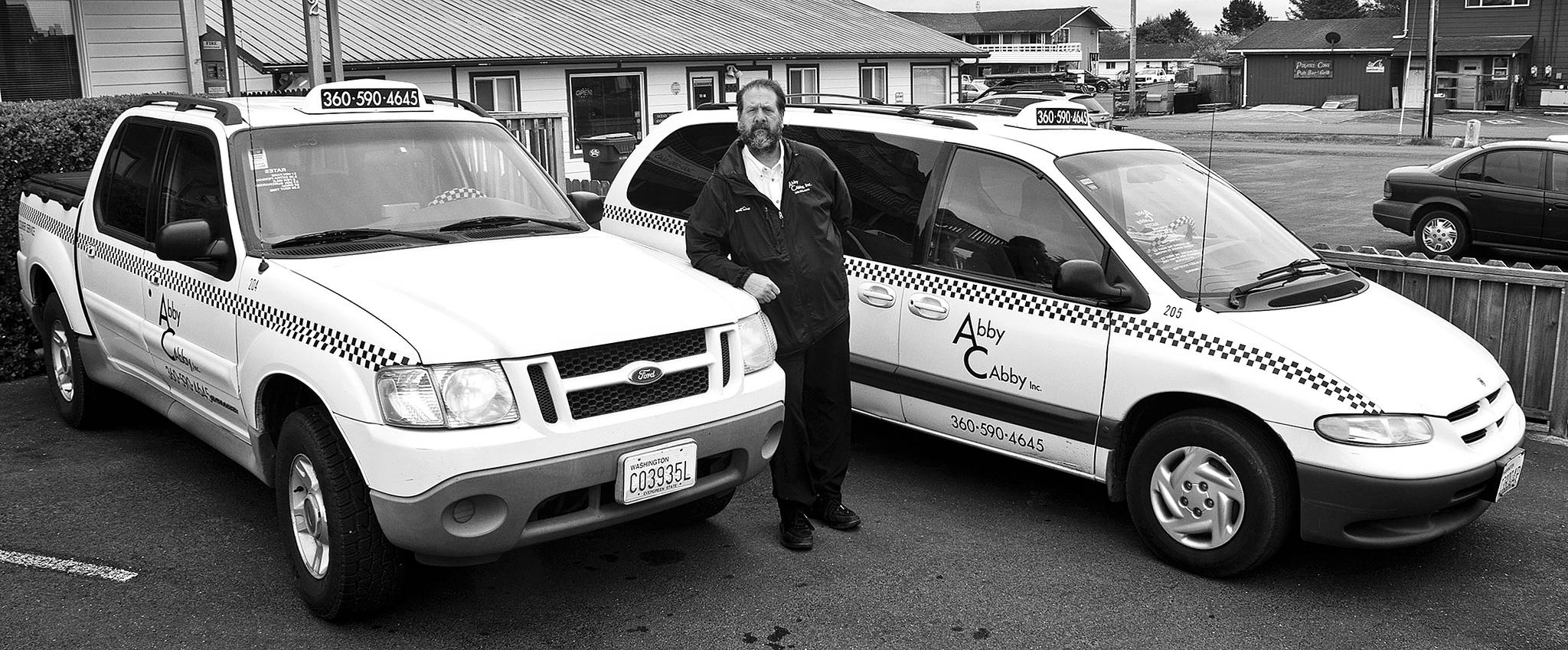 (Scott D. Johnson | Grays Harbor News Group) Abby Cabby General Manager Jim Monroe with part of the Abby Cabby fleet in front of the taxi service’s new North Coast office at 802 Ocean Shores Blvd. NW.