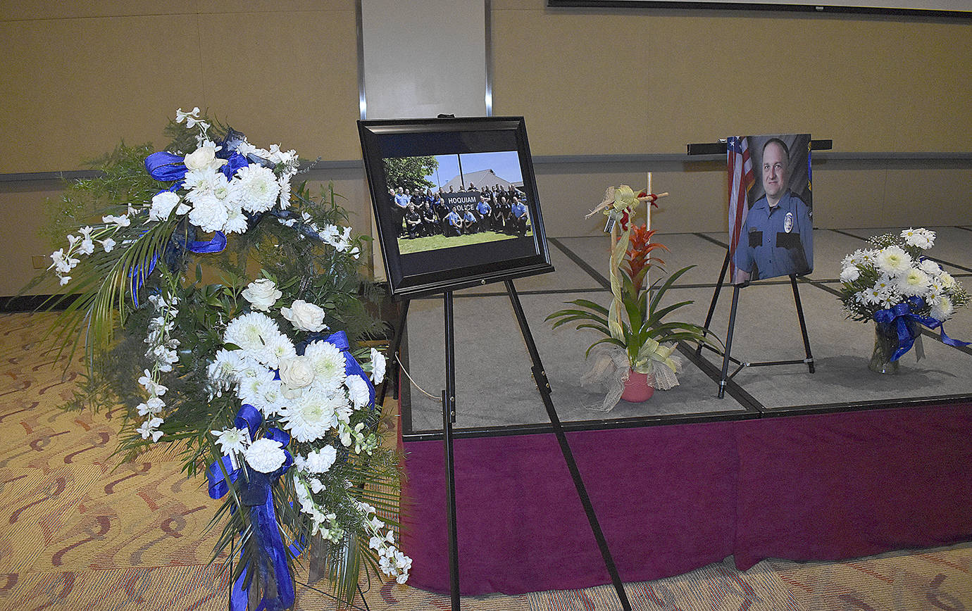 DAN HAMMOCK | GRAYS HARBOR NEWS GROUP                                 Flowers and photos lined the stage at Hoquiam Police Officer Phil High’s memorial service in Ocean Shores Saturday. Hoquiam Police Chaplain Sean Hollen delivered the invocation.